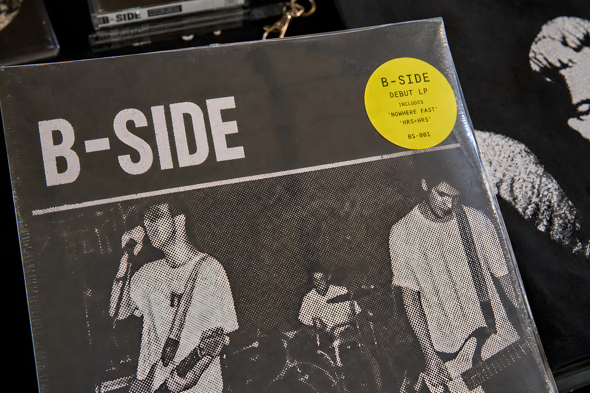 B-SIDE device macro: a vinyl sleeve close up, mono B-SIDE wordmark, halftone band photo, acid-yellow hype sticker